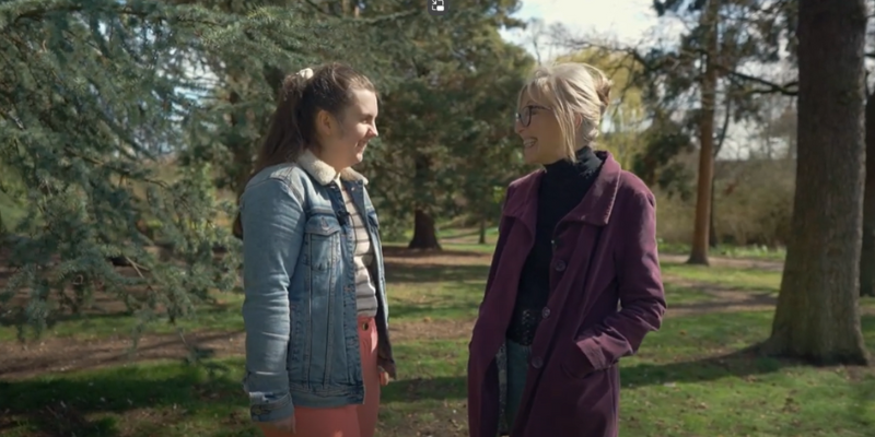 Two women stood facing each other outside, both smiling.