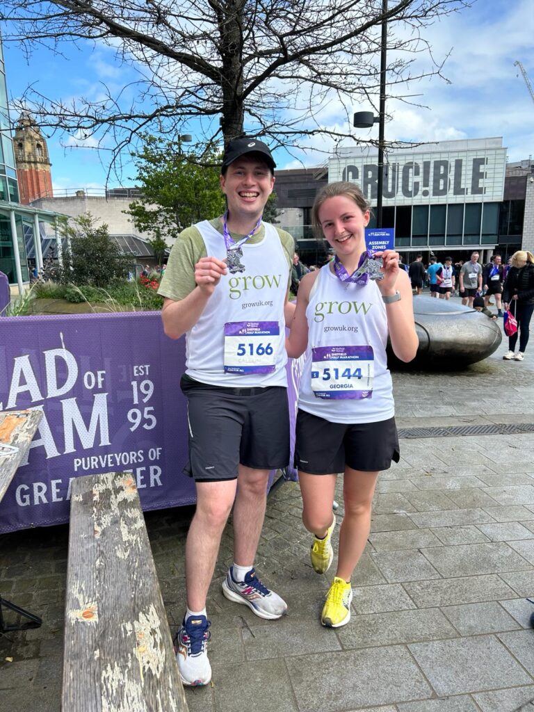 Male and female runners stood outside holding their medals