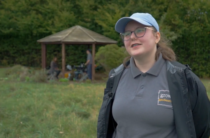 Female wearing grey polo shirt and rain coat stood smiling outdoors with a pergoda in the background_Grow Sheffield