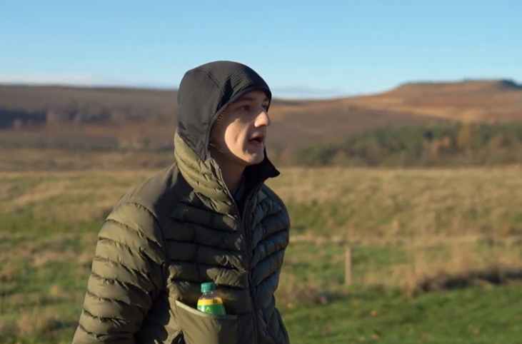 Male wearing a hood and jacket stood outdoors with moorland in the background_Grow Sheffield