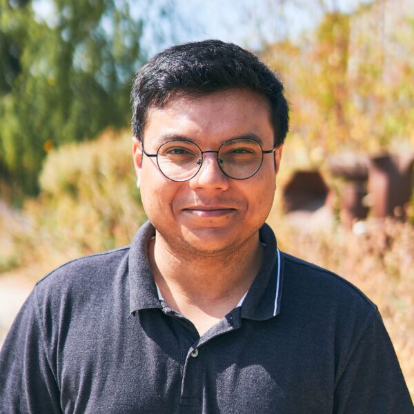 Man wearing glasses and dark polo shirt stood outside